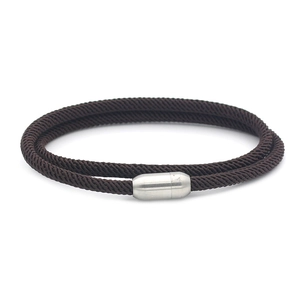 Detailed view of dark brown braided bracelet with silver cylindrical magnetic clasp