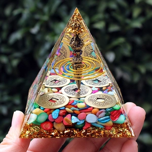 Detailed view of an 8cm crystal pyramid featuring copper coins and a vajra pestle inside