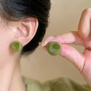 Close-up of green velvet flocked round stud earrings showing plush texture and size