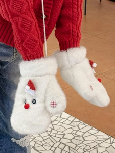 Close-up of white plush Christmas mittens with snowman face and red hat on model