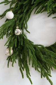 Close-up of green PE pine branches with silver and white Christmas ornaments decor
