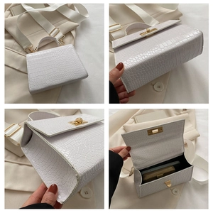 Detail view of white crocodile pattern bag featuring gold hardware and wide woven strap
