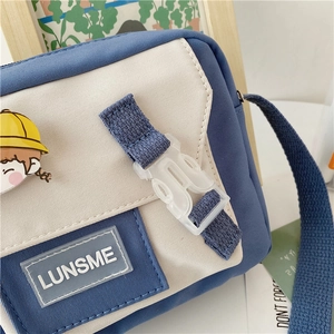 Detail of blue canvas messenger bag with cute cartoon badge and LUNSME rubber logo