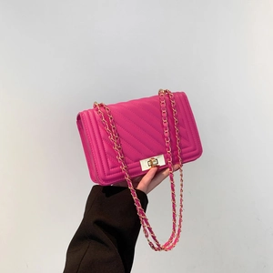 Close-up of rose red quilted shoulder bag with gold chain and rotating metal lock
