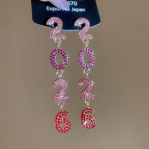 Gros plan des boucles d'oreilles 2026 avec strass en dégradé de couleurs et pompons