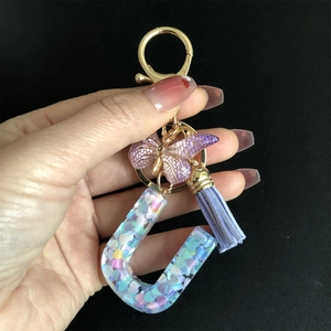 Detail of resin letter U keychain with purple butterfly charm and heart sequins inside