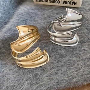 Detail der unregelmäßigen Wellenstruktur auf goldenen und silbernen Metallarmreifen