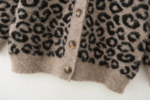 Gros plan du cardigan en maille léopard montrant la texture douce et les boutons ambre