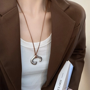 Close-up of polished silver irregular C-pendant with brown leather cord necklace
