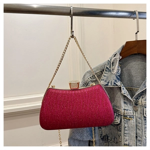 Detail of rose red evening clutch with gold metal frame, diamond buckle, and chain strap