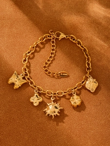 Détail macro du bracelet en acier inoxydable doré avec breloques papillon et soleil