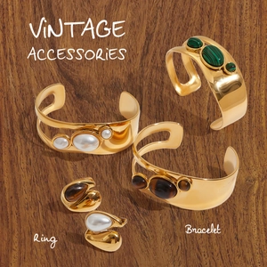 Dettaglio di set gioielli vintage con perla e malachite su superficie in legno