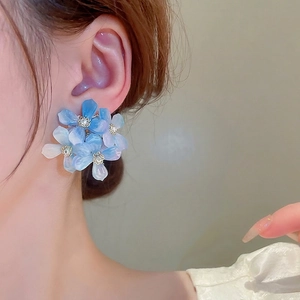 Blue gradient acrylic flower earrings with small pearl accents on a female model