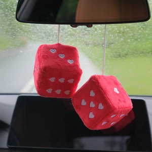 Detail of red plush car dice with white hearts hanging from a rearview mirror