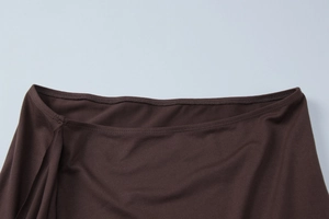 Detailed close-up of dark brown stretch fabric with neat double-stitch hem sewing