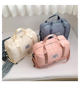 Three travel duffle bags in cream, blue and pink with embossed star patterns