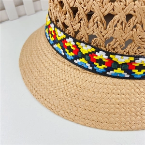 Detail of hollow-weave straw hat with a colorful geometric patterned ribbon trim