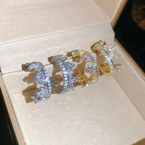 Detailed view of silver and gold C-shaped earrings with cubic zirconia in a jewelry box