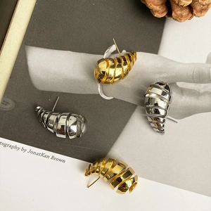 Macro detail of spiral shell design stud earrings in polished gold and silver finish