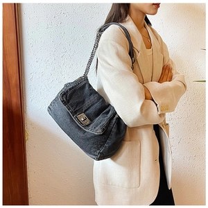 Detail of dark denim shoulder bag with metal chain strap and vintage wash texture