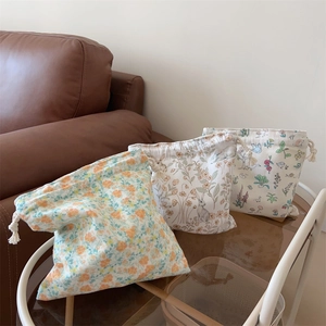 Vue détaillée de trois pochettes de rangement en coton à fleurs avec cordon de serrage