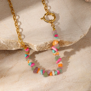 Macro view of multi-color natural stone fragments and golden clasp detail on the necklace