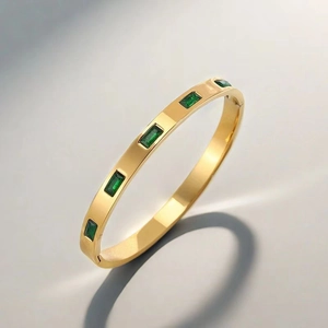 Detail of 18k gold plated titanium steel bangle with five emerald-cut green zircons