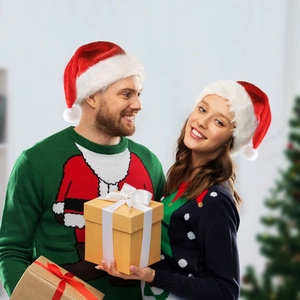 Matching Christmas LED plush hats and sweaters worn by a couple holding gift boxes