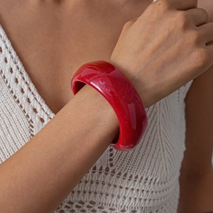 Close-up of translucent deep red acrylic wide bangle with marble texture on wrist