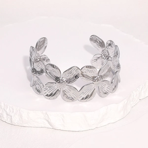 Bracelet jonc ouvert à fleurs évidées en acier inoxydable poli sur socle en pierre