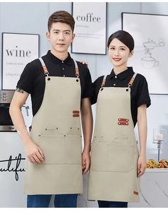 Detail of beige canvas apron with brown leather straps and multi-pocket design