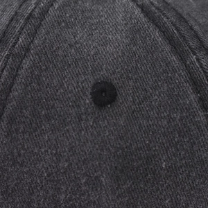 Macro shot of a grey washed baseball cap showing stitched eyelet and twill fabric texture
