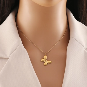 Close-up of golden butterfly pendant necklace worn by a model on a delicate bead chain