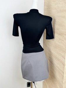 Back view of a black high-neck half-sleeve T-shirt paired with a grey skirt on a mannequin