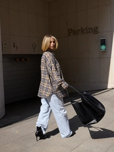 Close-up of grey and yellow plaid shirt paired with a black leather tote bag on street