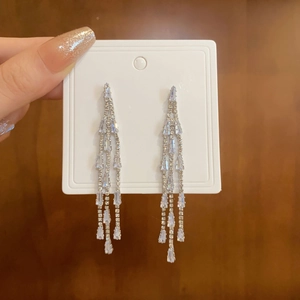 Detailed macro view of long silver tassel earrings with shimmering cubic zirconia crystals