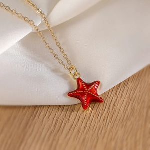 Collier avec pendentif étoile de mer dorée et émail rouge sur soie et bois texturé
