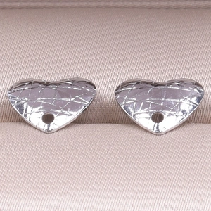 Macro shot of silver heart charms with quilted texture on beige satin lining