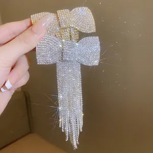 Barrette à cheveux nœud avec pompons et strass en finitions dorée et argentée