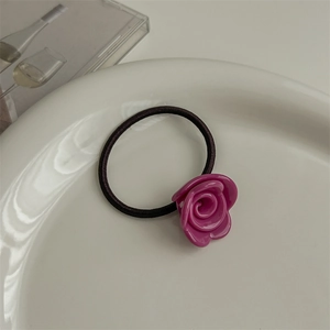Detail of high-elasticity hair tie with glossy purple rose on a white ceramic plate