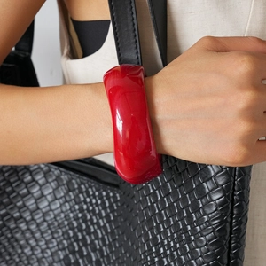 Close-up of wide red acrylic geometric bangle worn on wrist for a minimalist modern style