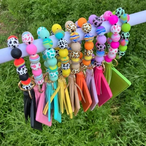 Colorful silicone beaded wristlet keychain with PU leather tassels and card holders on grass
