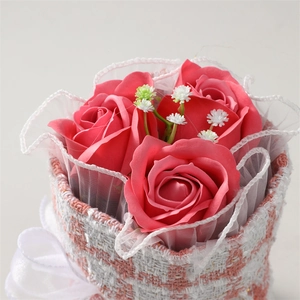 Close-up of pink soap rose bouquet with lace and baby's breath in a woven basket