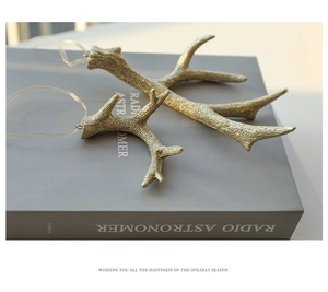 Pair of golden glitter reindeer antler ornaments with sheer ribbons on a grey book