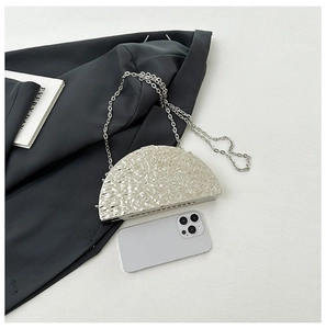 Detailed view of silver metallic evening bag with chain strap and phone for size reference