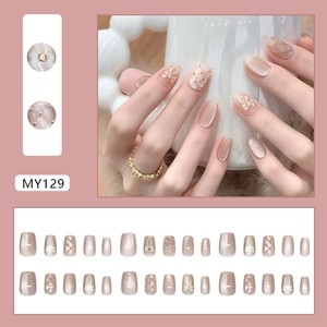 Nude pink cat eye press-on nails with diamond bows and pearl accents for women
