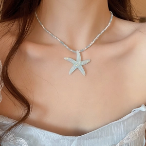 Close-up of a blue resin starfish pendant on a blue and white beaded necklace chain