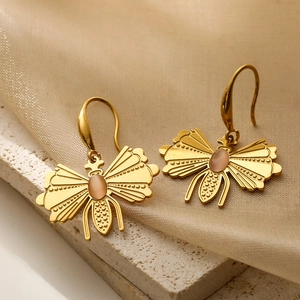 Elegant gold butterfly earrings with pink crystal on silk and stone background