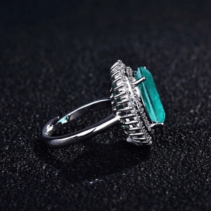 Detailed side view of emerald-cut green gemstone ring with pavé halo setting