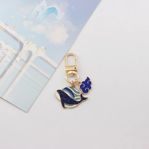 Detail of blue enamel whale keychain with golden glitter and lucky cloud charm